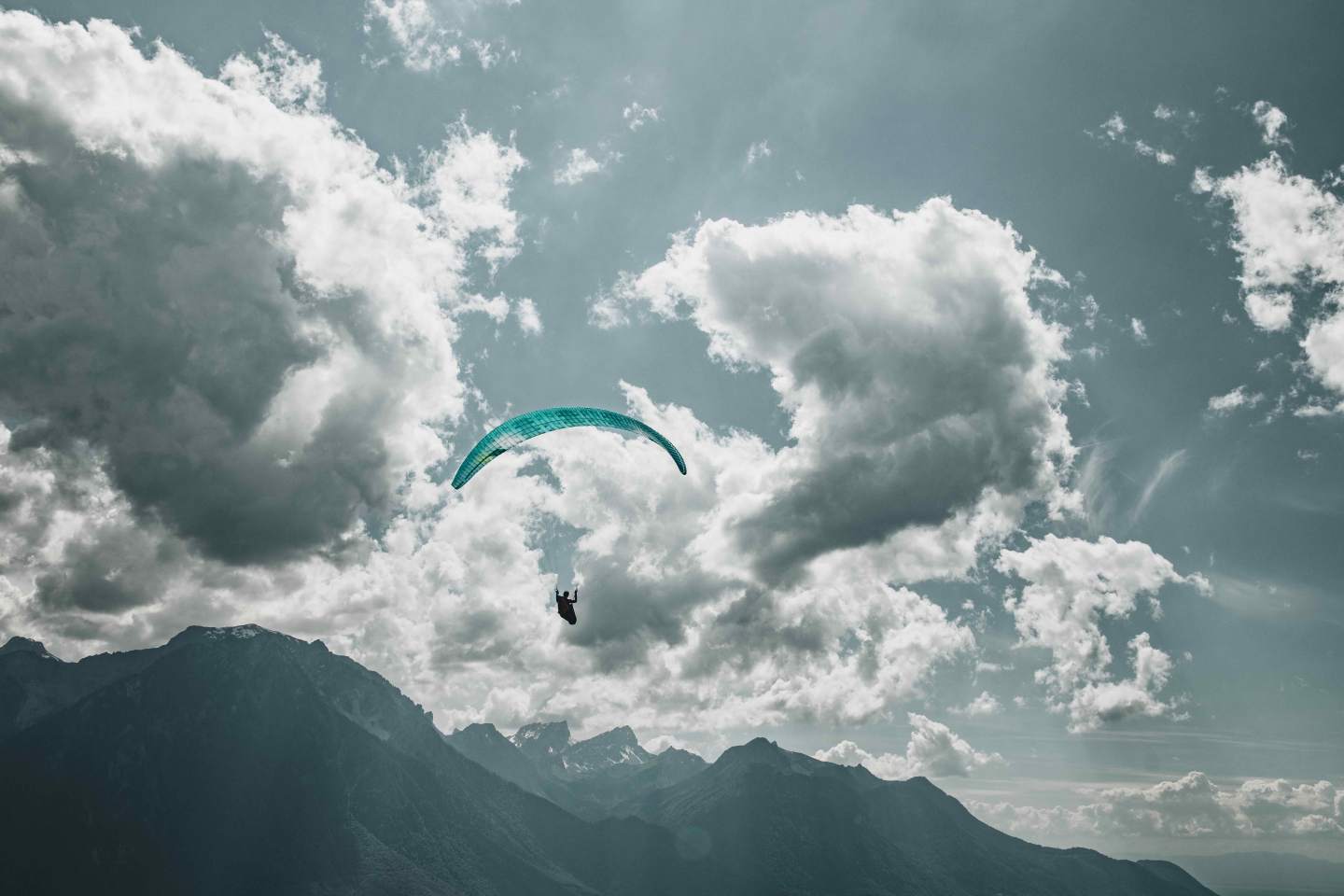 Parapente évoluant entre les nuages au-dessus des Alpes
