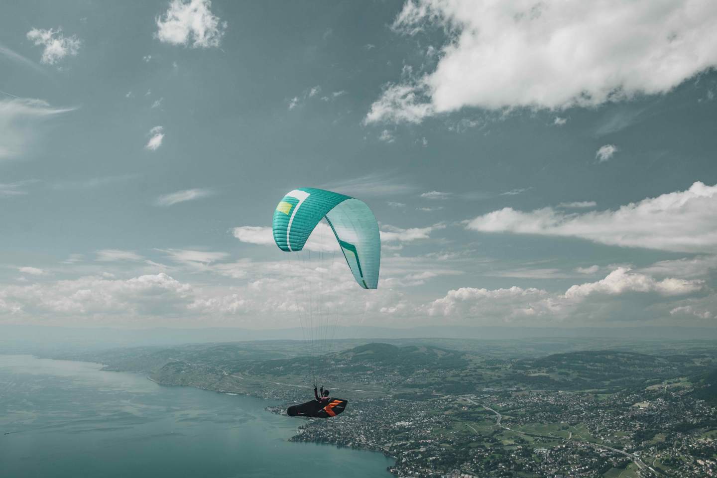 Parapente léger survolant une vallée et son lac