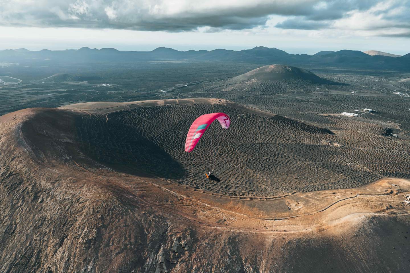 Parapentiste en vol sous une aile légère Niviuk Artik 7 P au-dessus des reliefs montagneux, la récompense d’une montée à pied en hike & fly.