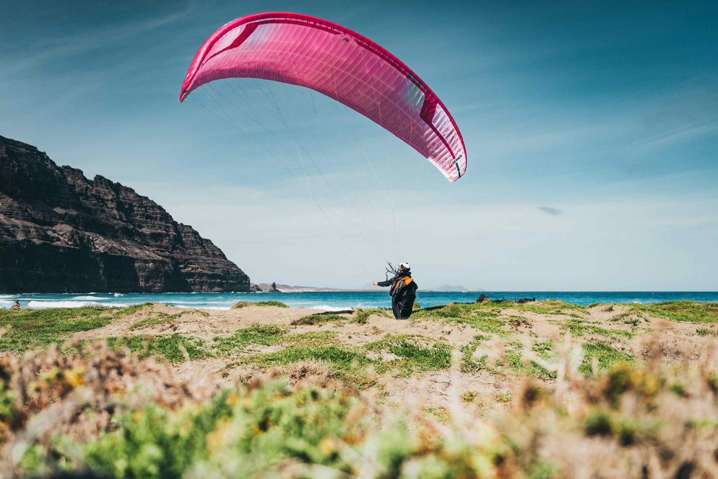 Pilote gonflant sa voile au décollage sur une crête herbeuse, marche et vol