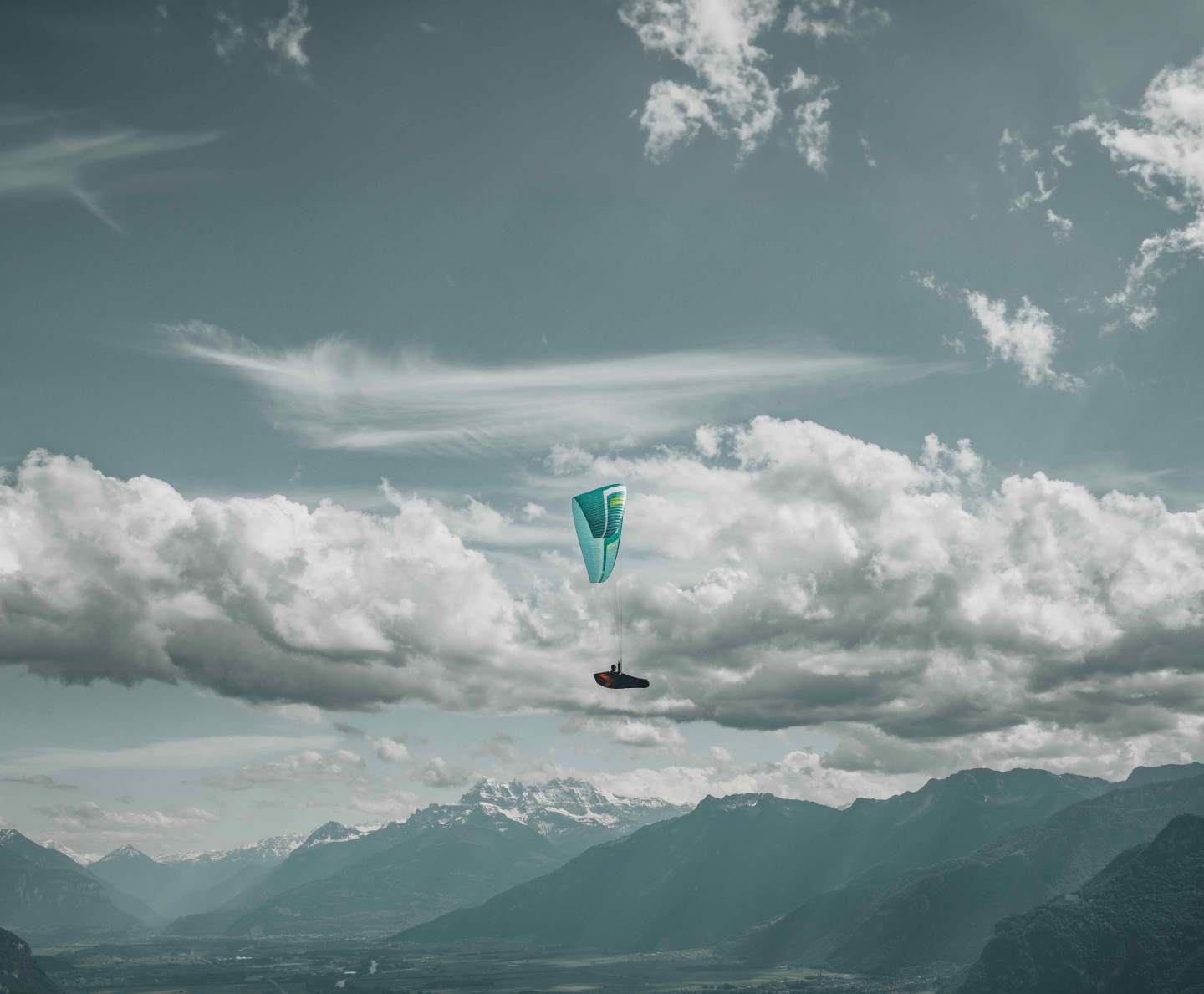 Parapente aile jaune et grise en vol matinal au-dessus d’une crête alpine, lumière rasante et air calme typique de la fenêtre du matin.