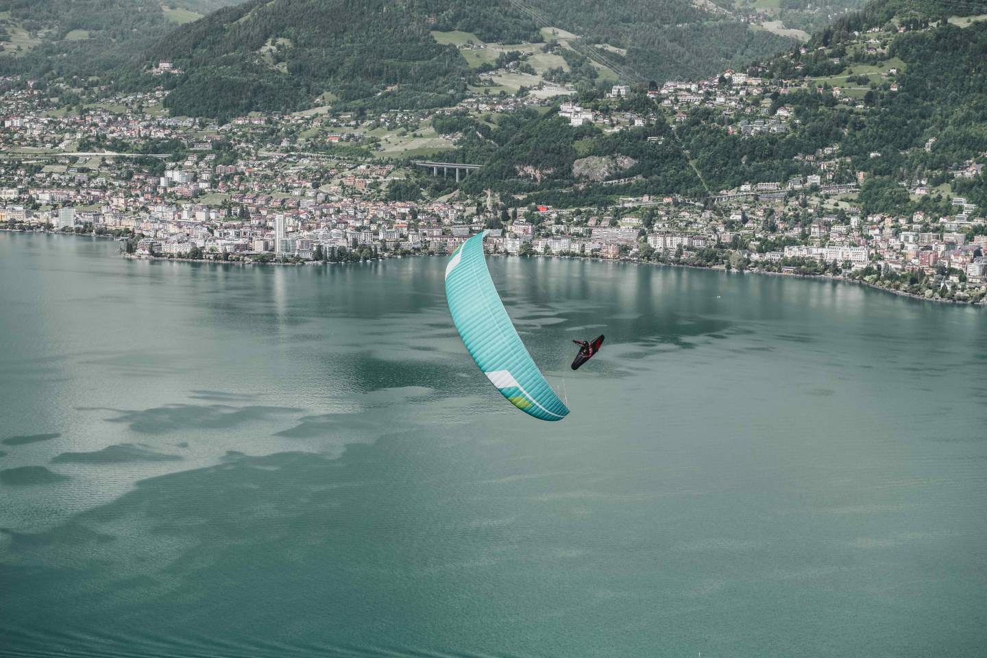 Parapentiste en vol au-dessus d’un relief de montagne, aile ouverte dans un ciel dégagé de fin de matinée