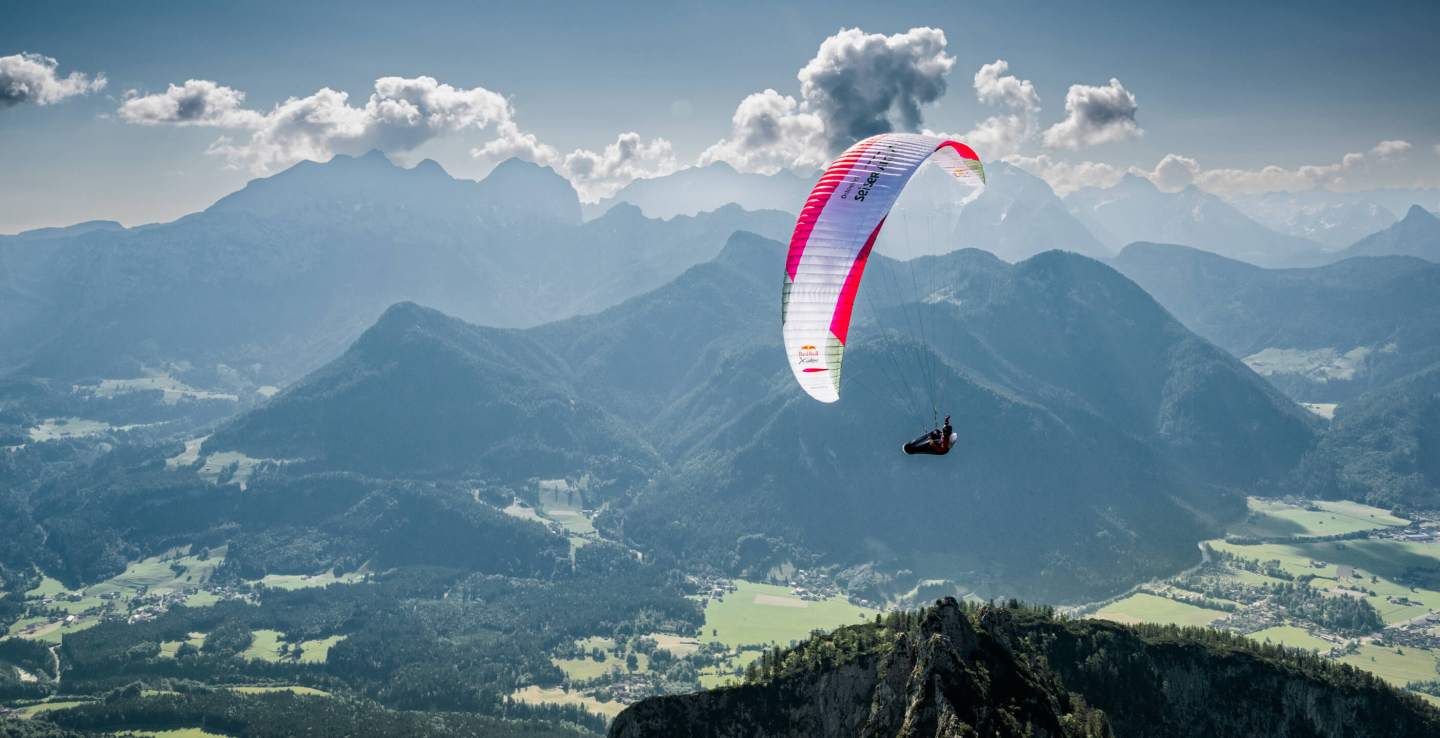 Parapente aux couleurs vives en vol au-dessus d’un relief de montagne, image emblématique des courses de marche et vol