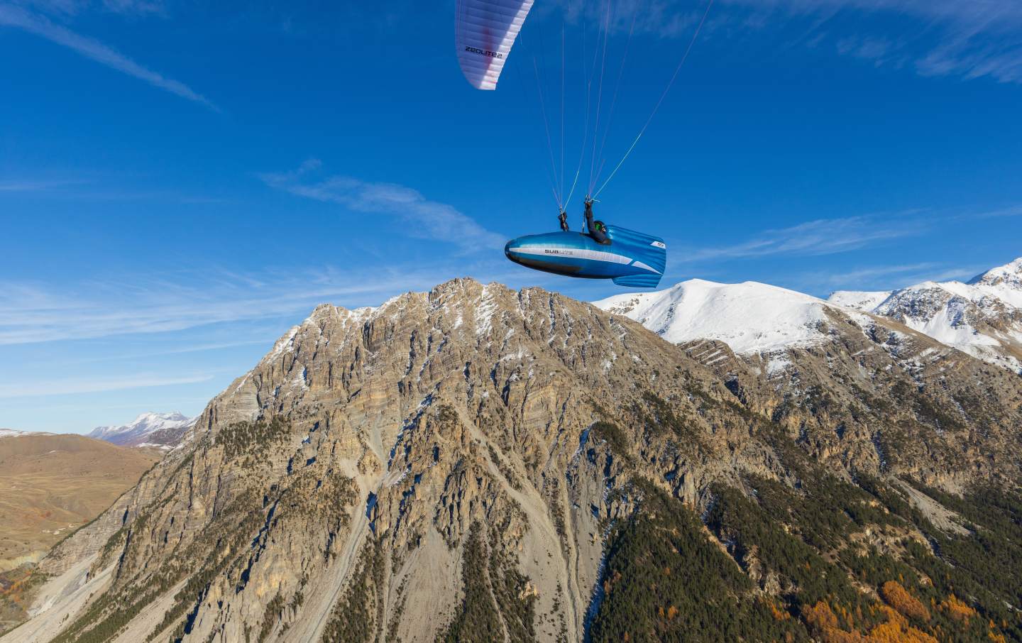 Pilote de hike & fly en montagne avec sa voile légère, face aux crêtes balayées par le vent